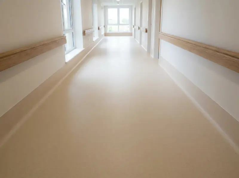 Lange gang in een zorginstelling met naadloos gelast homogeen vinyl en een opgetrokken plint